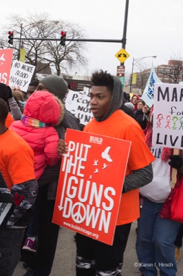 Black adolescent holding sign Put the Guns Down